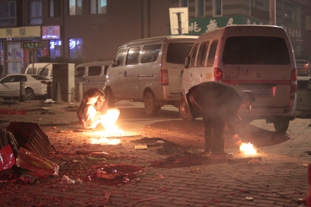 Chinese men lighting fires in the street.